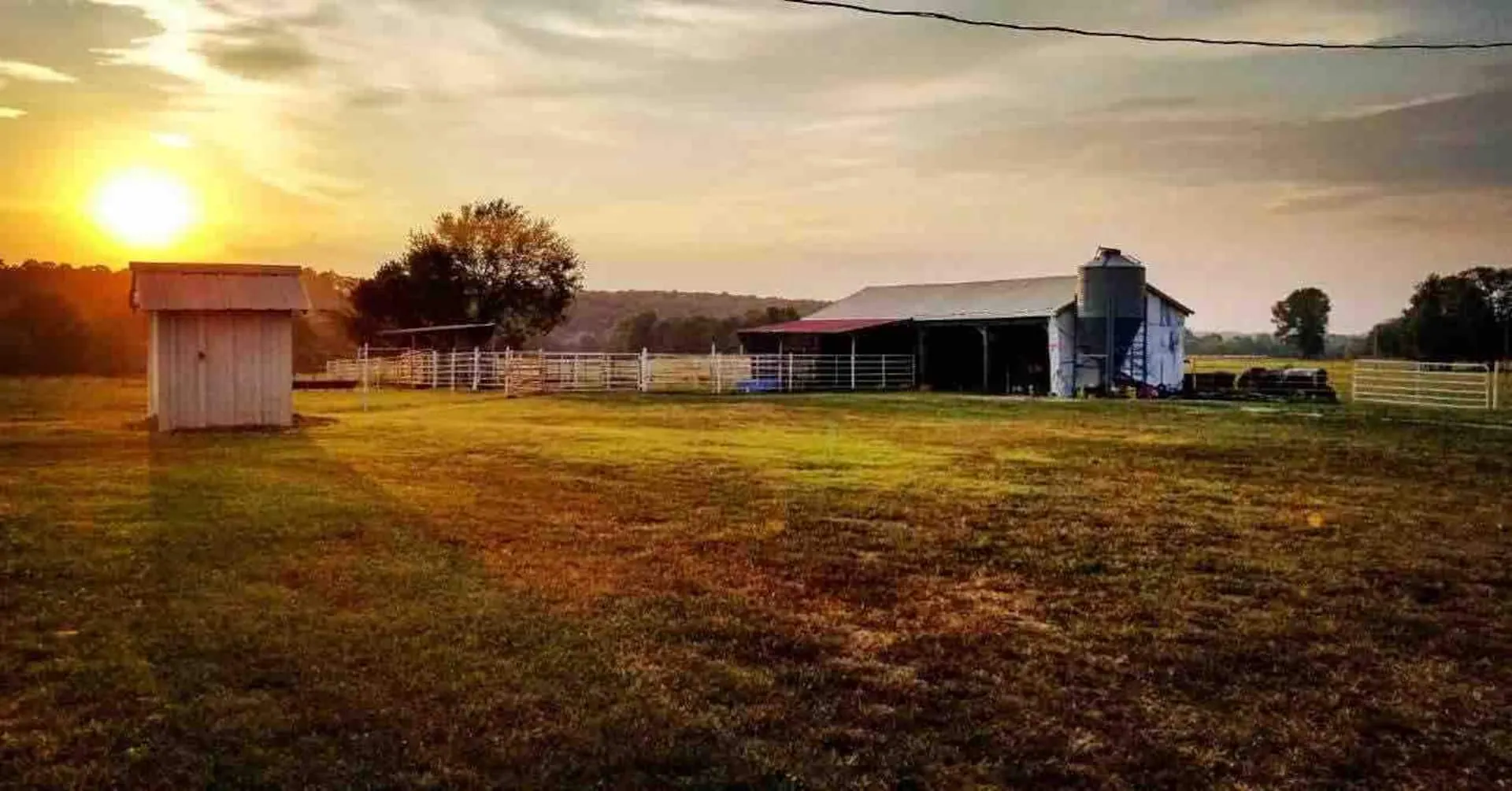 Sunset over the farm outbuildings, barn and grain bin