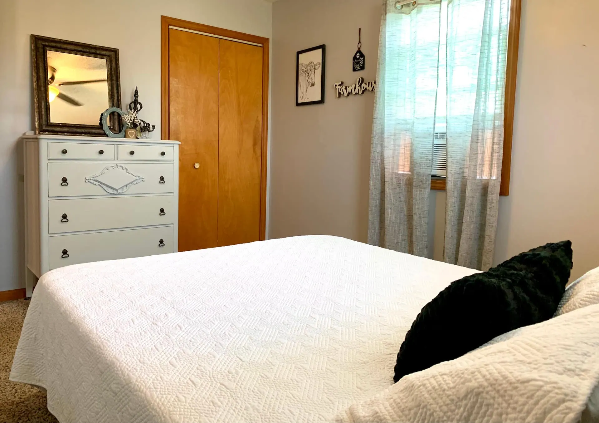 Bedroom one detail: an antique white dresser and mirror beside the queen bed