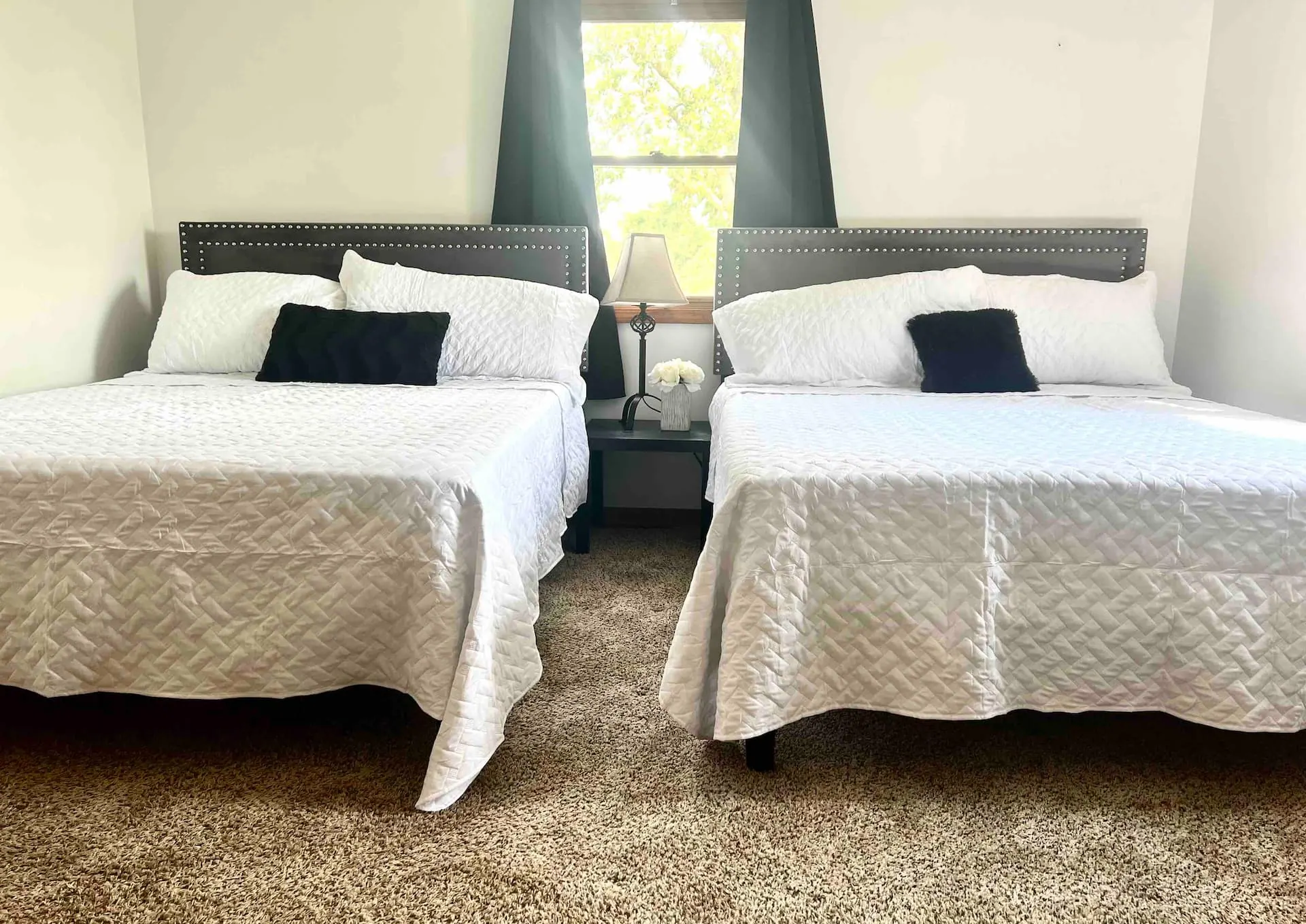 Bedroom two: a pair of queen beds with upholstered headboards flanking a bright window