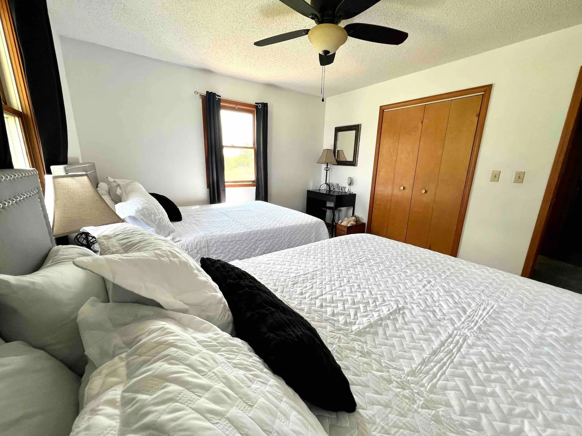 Bedroom two with two queen beds made up in white quilts beneath a ceiling fan