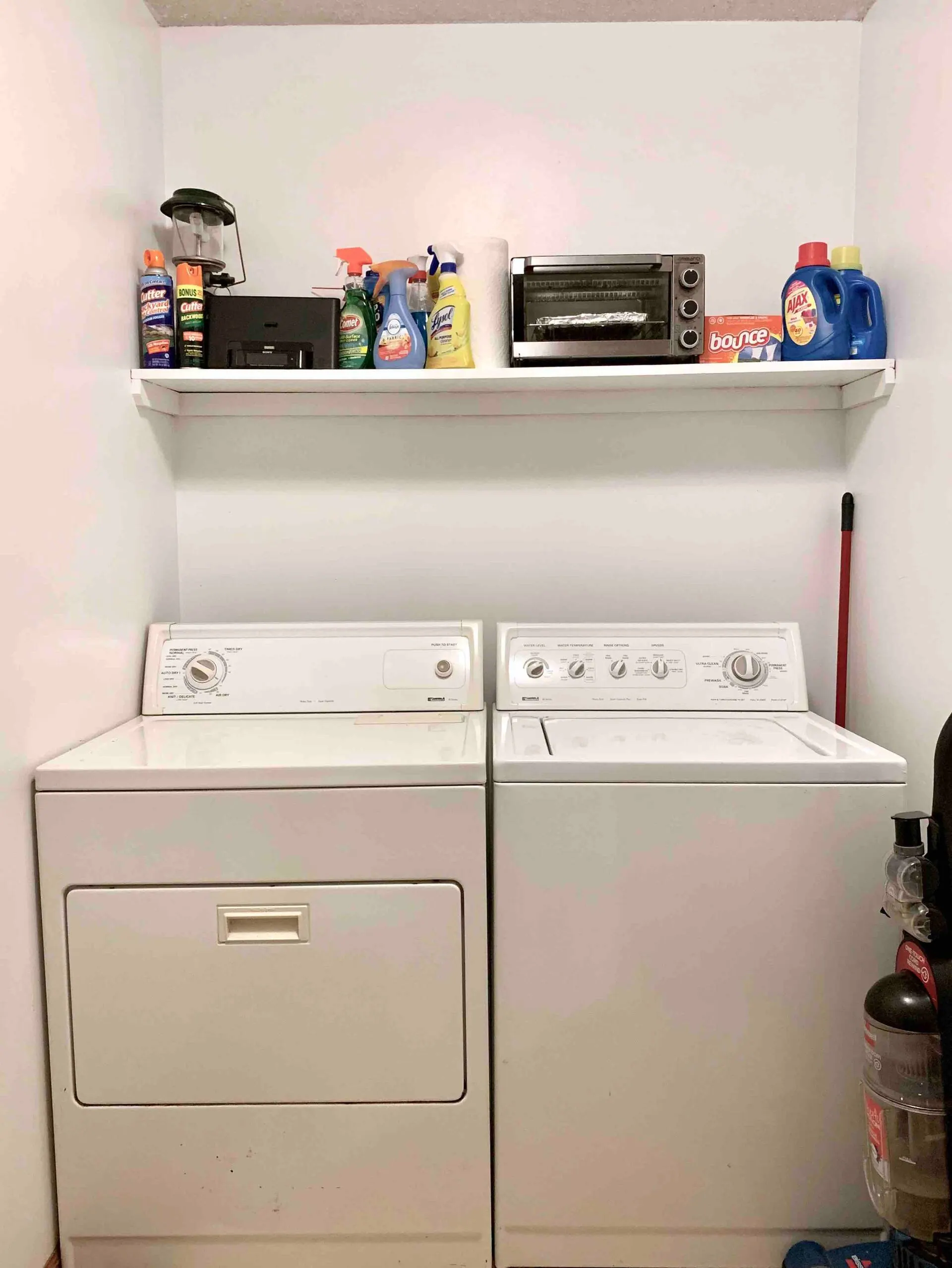 Laundry room with a full-size washer and dryer and a stocked supply shelf — the farm map hangs in here