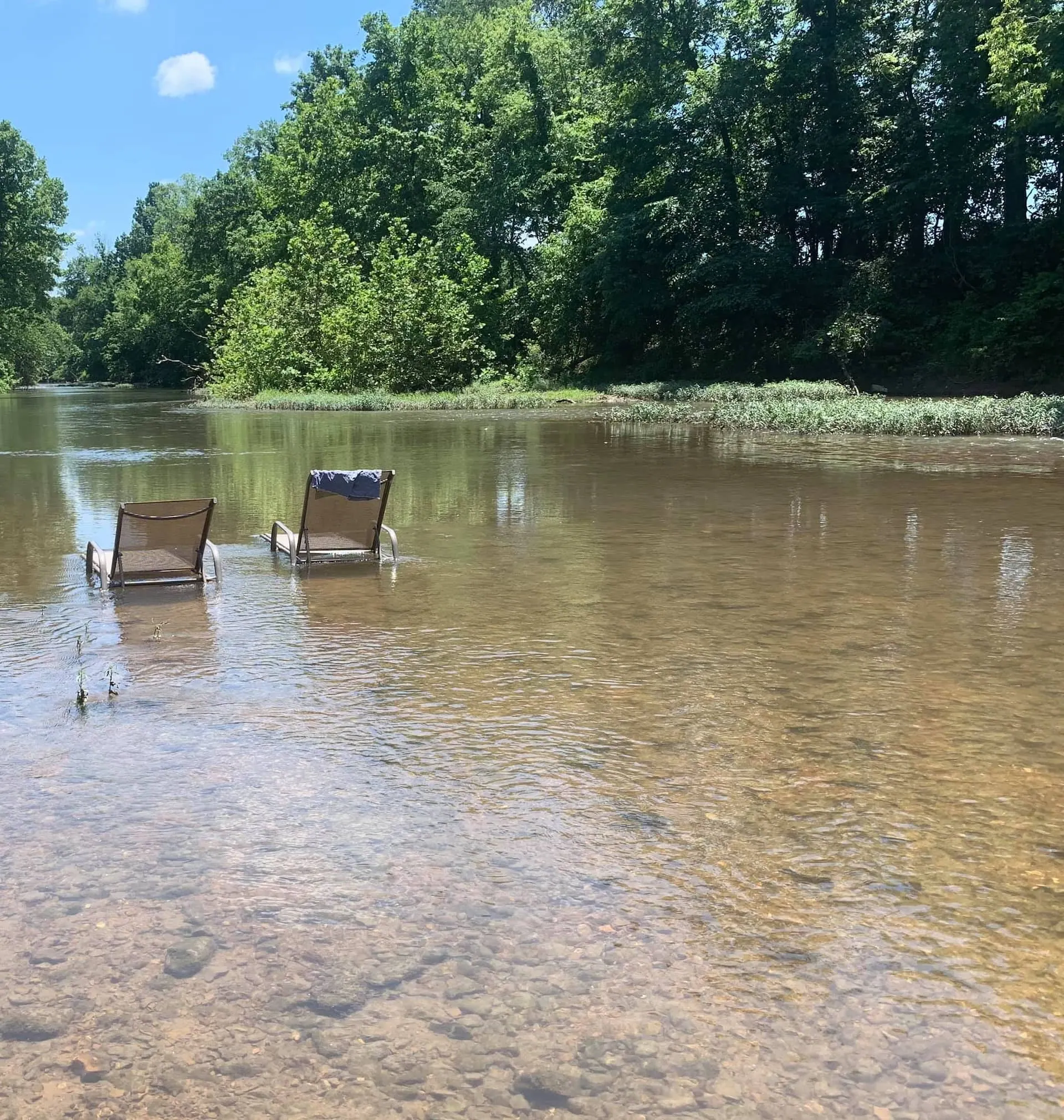 Two camp chairs standing in the clear, shallow water at the private spot on the Sac River