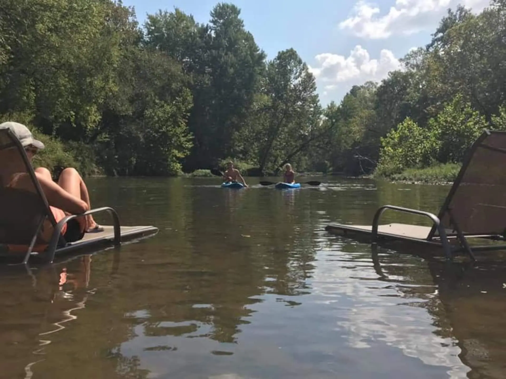 Guests relaxing in lawn chairs set right in the shallow Sac River while others float downstream on tubes