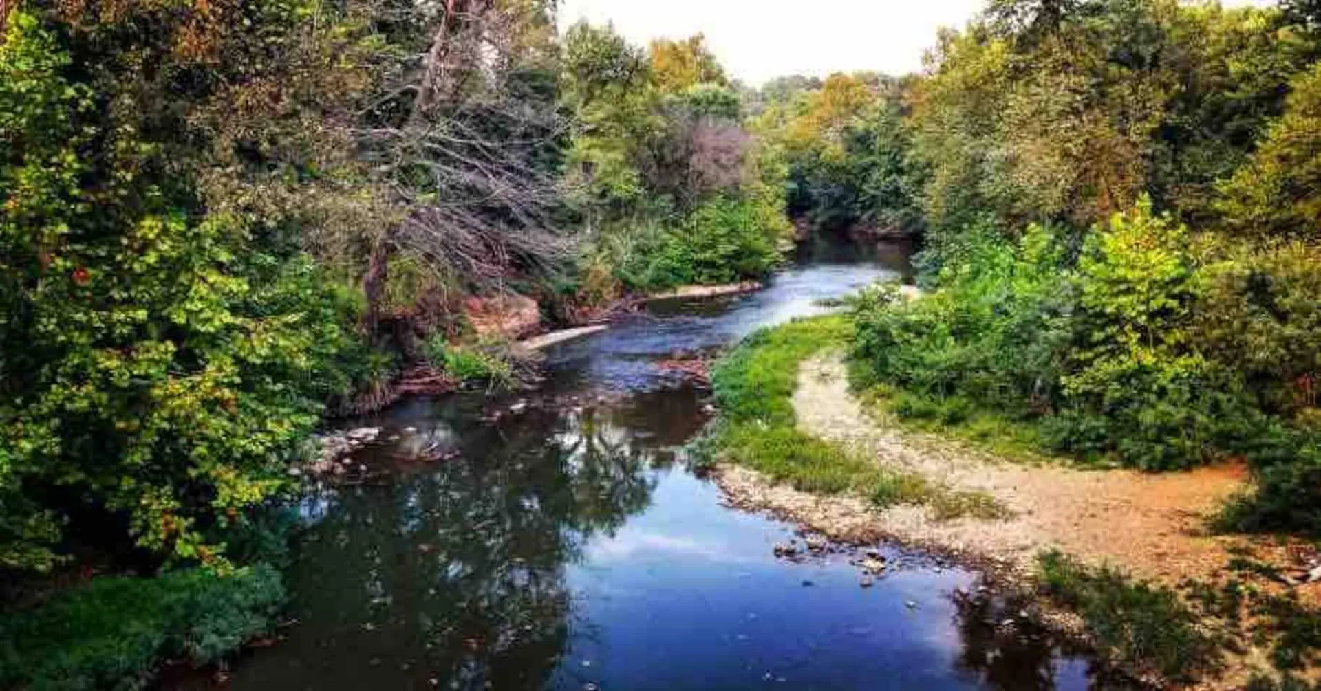 View of the Sac River from the bridge, a gravel bar curving beneath autumn timber — the put-in for floating down to the private gravel bar