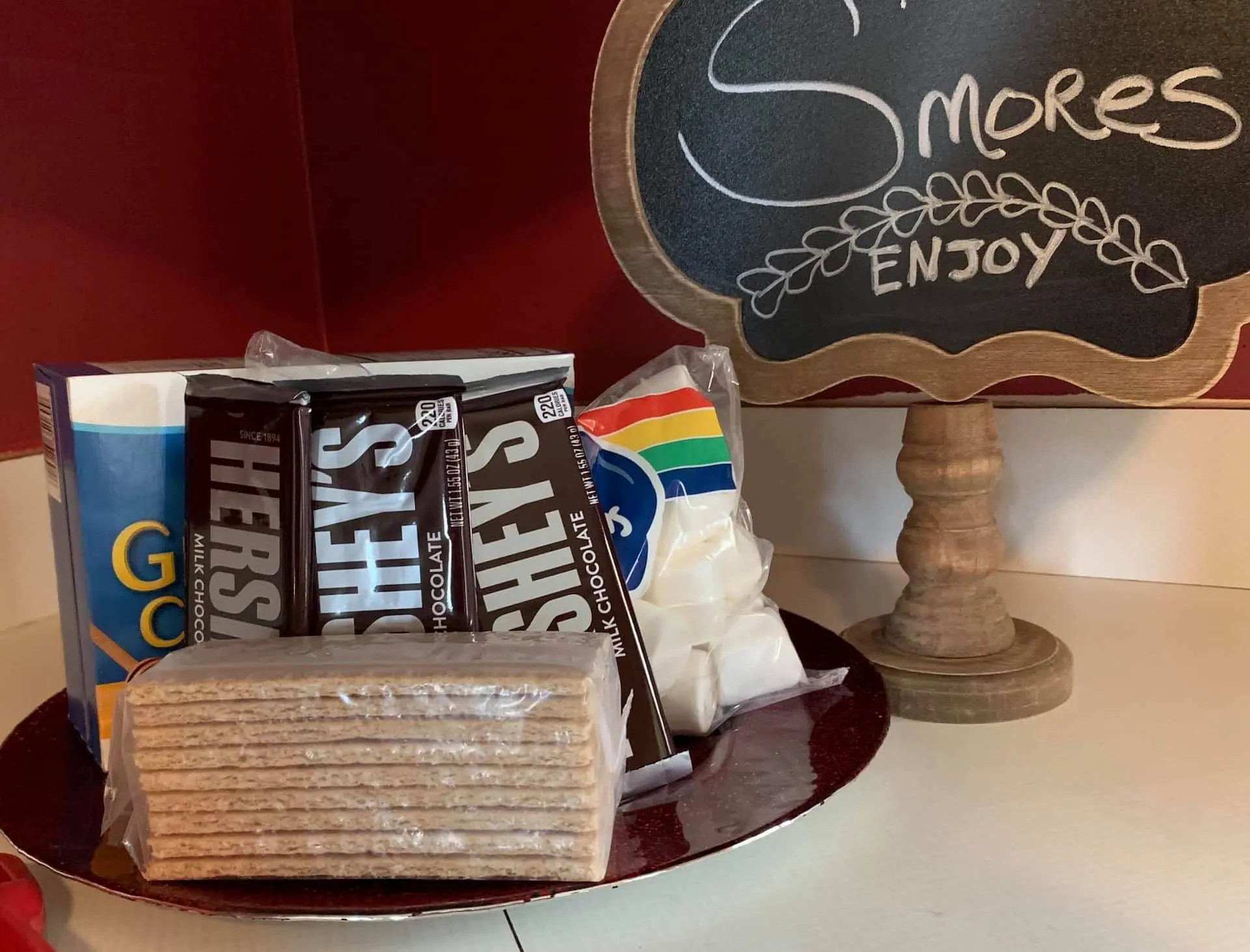 A s’mores station with graham crackers, marshmallows and chocolate laid out under a chalkboard sign